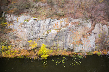 View of the river and the canyon cliffs. The river flows at the foot of the cliffs. Leaves are floating on the river. Autumn landscape.