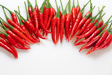 Red hot chili pepper on white background. Horizontal row of chili peppers, top view. Red ripe peppers with green stems with copy space.