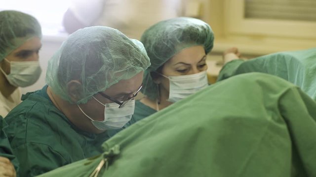 Portrait of female and male surgeons during surgical operation in operating room.