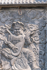 Da Nang, Vietnam - March 10, 2019: Chua An Long Chinese Buddhist Temple. Closeup of stone chiseled image of East heavenly king Dhrtarastra, a stern looking lute playing man.