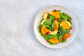 Salad with arugula, persimmon, avocado and pomegranate seeds