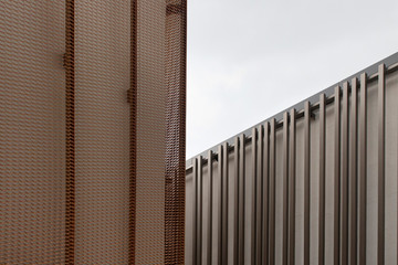 Close up view of modern architectural details. Bronze colored metal mesh and metal frames are in the view.