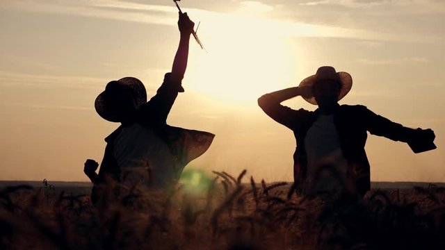 eam work. Two farmers stand at sunset in a wheat field, and discuss the new crop.. Farmers use new technologies in agriculture. Growing organic products.