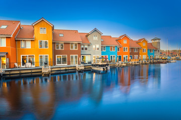 Lovely and colorful buildings reflecting on harbour water at twilight, Reitdiephaven, Groningen, Netherlands.