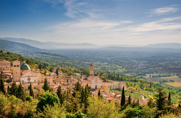 Fototapeta na wymiar View of Assisi charming historic center and Umbria countryside seen from Rufinus Hill with haze in the background