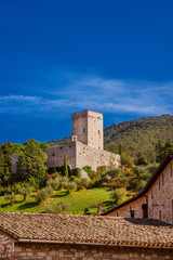 Assisi ancient medieval walls ruins at the top of the town with blue sky above