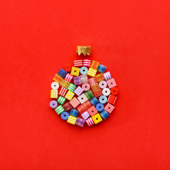 Christmas Bauble made of decoration elements on red background. Flat lay. Contemporary design. Contemporary art. Creative conceptual and colorful collage.
