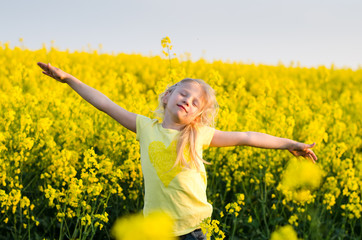 Naklejka na ściany i meble adorable charming blond girl with hands up in yellow meadow