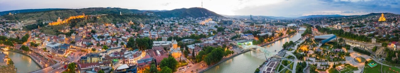The evening panorama of the old town on Sololaki hill, crowned with Narikala fortress, the Kura river reflects the evening city lights and cars traffic with blure in Tbilisi, Georgia