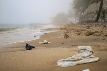 Environmental disaster. black boot, plastics and waste in a foggy beach, full of waste