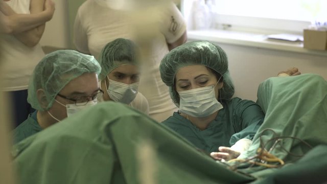 Surgeons and nurse performing gynecological surgical procedure in operating room, close up.