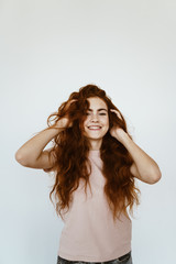 schoolgirl laughs and fumbles hair with her hands. bright studio
