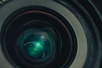 Beautiful camera lens with geen and pink light of glass on a black background. Macro photography...