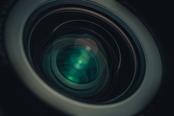 Beautiful camera lens with geen and pink light of glass on a black background. Macro photography...