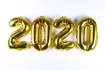Concept of a new year greeting card with golden foil air balloons in the shape of 2020 digits with a lot of copy space for text. Top view, flat lay.
