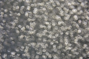 Blurred abstract background with sparkle shiny bokeh. Romantic holiday bokeh background with soft focus and magical shimmering. Christmas and new year card. Grey bokeh backdrop 