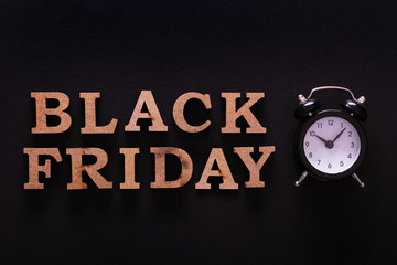 Black friday sale concept. Fourth Friday of November, beginning of Christmas shopping season since 1952. Old alarm clock, text on paper textured background. Copy space, close up, top view, flat lay