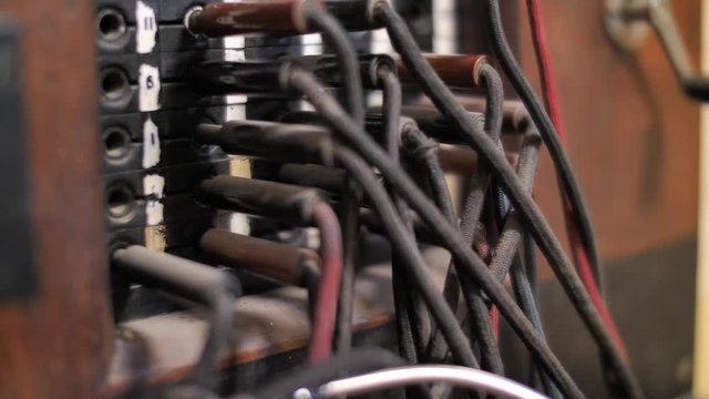 Close up on hand inserting plug into socket of retro telephone exchange