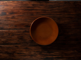 empty brown plate on wood table. plato marrón vacío en la mesa de madera