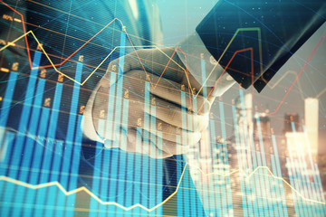 Double exposure of financial chart on cityscape background with two businessmen handshake. Concept of financial analysis and investment opportunities
