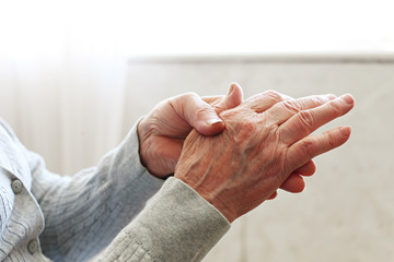 Elderly woman applying moisturizing lotion cream on hand palm, easing aches. Senior old lady experiencing severe arthritis rheumatics pains, massaging, warming up arm. Close up, copy space, background - obrazy, fototapety, plakaty