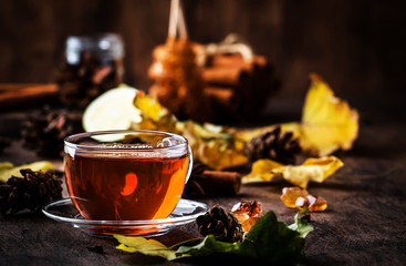 Autumn hot black tea in glass cup, old wooden table background, selective focus