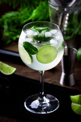 Martini royale alcoholic cocktail with white vermouth, prosecco, lime, mint and ice. Old wooden table background, bar tools, selective focus. All names refer to cocktails, not trademarks