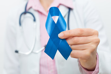 The doctor is holding a blue ribbon in his hand. The concept of prostate cancer. 