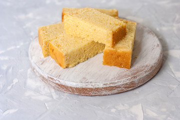 Freshly baked corn bread on a round wooden white board on a light gray background. Traditional baked goods in national cuisine of the USA.