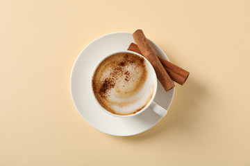 Cappuccino with cinnamon on beige background, space for text