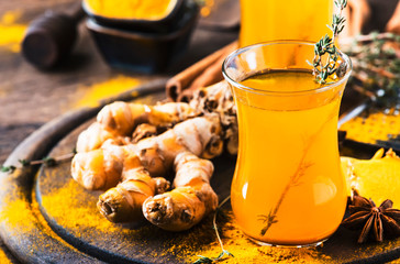 Healthy vegan turmeric golden tea with honey in glass cup on wooden tray. Herbal healing spicy tea