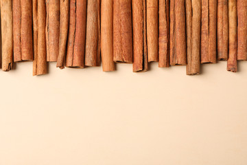 Cinnamon sticks frame on beige background, space for text