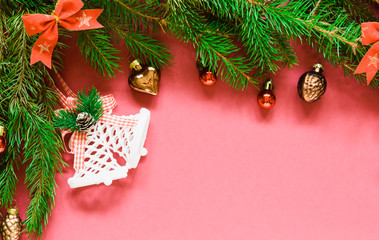 Fototapeta na wymiar top view, green branches of spruce together with New Year's toys and bows on a pink background