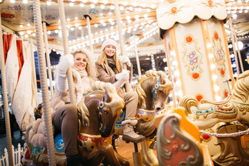 Photo of two women riding on carousel in park © snedorez