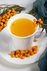 sea buckthorn tea in white cup with  berries with branch on natural napkin. a source of nutritional vitamins in the fall and winter