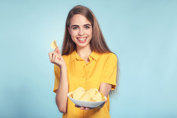Young beautiful girl with potato chips in bowl on blue background