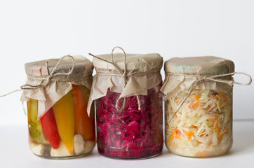 Homemade pickled and sauerkraut, pickled peppers in glass jars on a white background