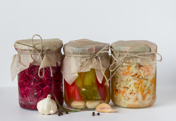 Sauerkraut, pickled cabbage and bell pepper in glass jars on a light background with copy space