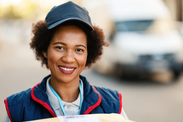 Portrait of smiling black delivery woman looking at the camera.