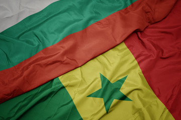 waving colorful flag of senegal and national flag of bulgaria.