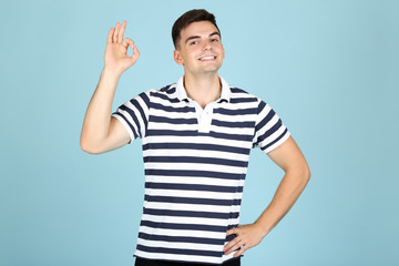 Naklejka premium Young man showing gesture OK on blue background