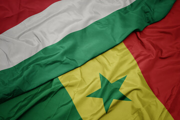 waving colorful flag of senegal and national flag of hungary.