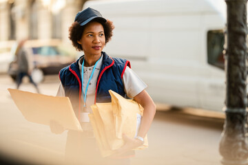 Female African American courier with packages for the delivery in the city.