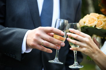 wedding background: hands of the bride and groom hold glasses with wine