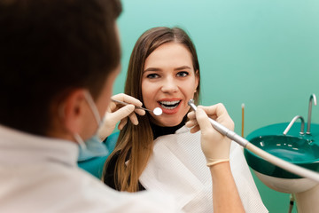 Dentist with a drill and a mirror is treating a patient teeth