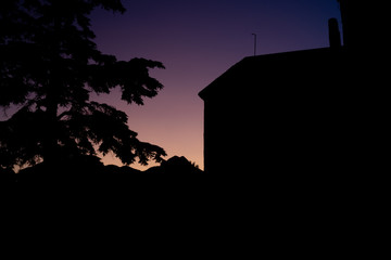 Purple sunset in the mountains with the contours of mountain, tree and building