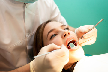 Young woman came to the dentist for examination. The dental doctor examines the patient close-up