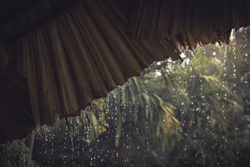 Rain drops from hut roof as vintage tropical background  