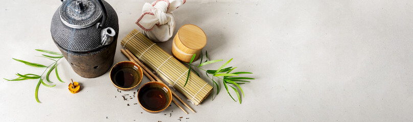 Still life with tea set, furoshiki wrapping present gift, scattered tea, bamboo mat, chopsticks,...