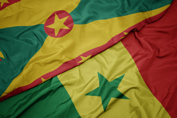 waving colorful flag of senegal and national flag of grenada.